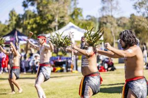 Aboriginal performers in traditional dress dancing at a community celebration.